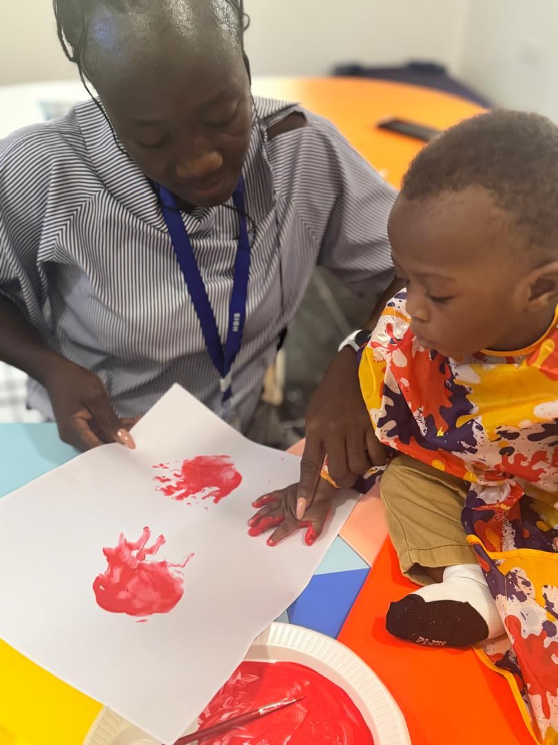 Teacher helping a young child with handprint painting