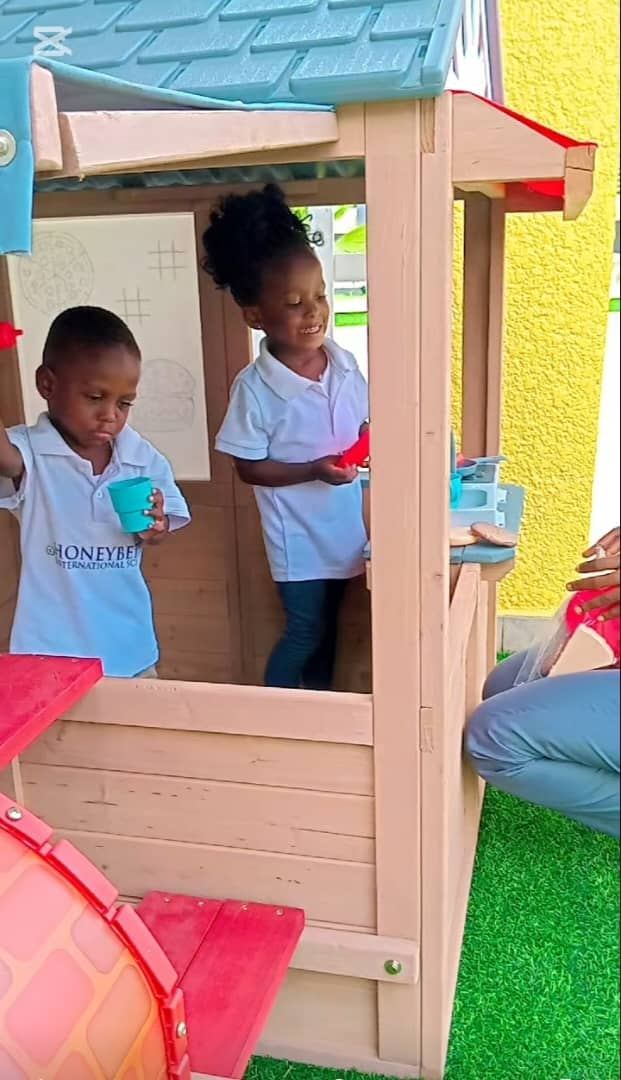 Young children playing around the campus playhouse