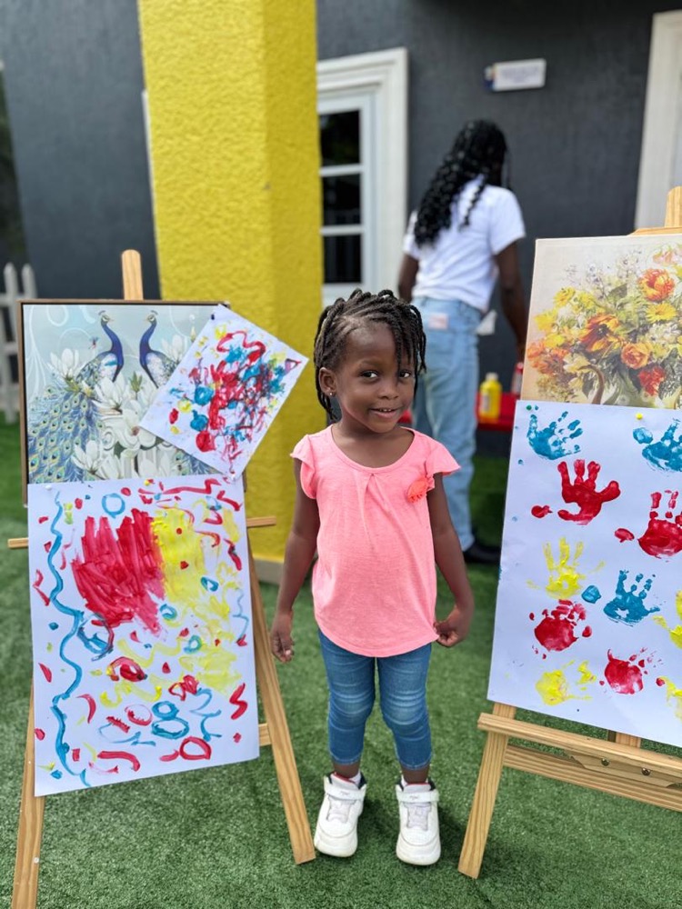 Young HoneyBerry learner standing proudly beside colourful artwork